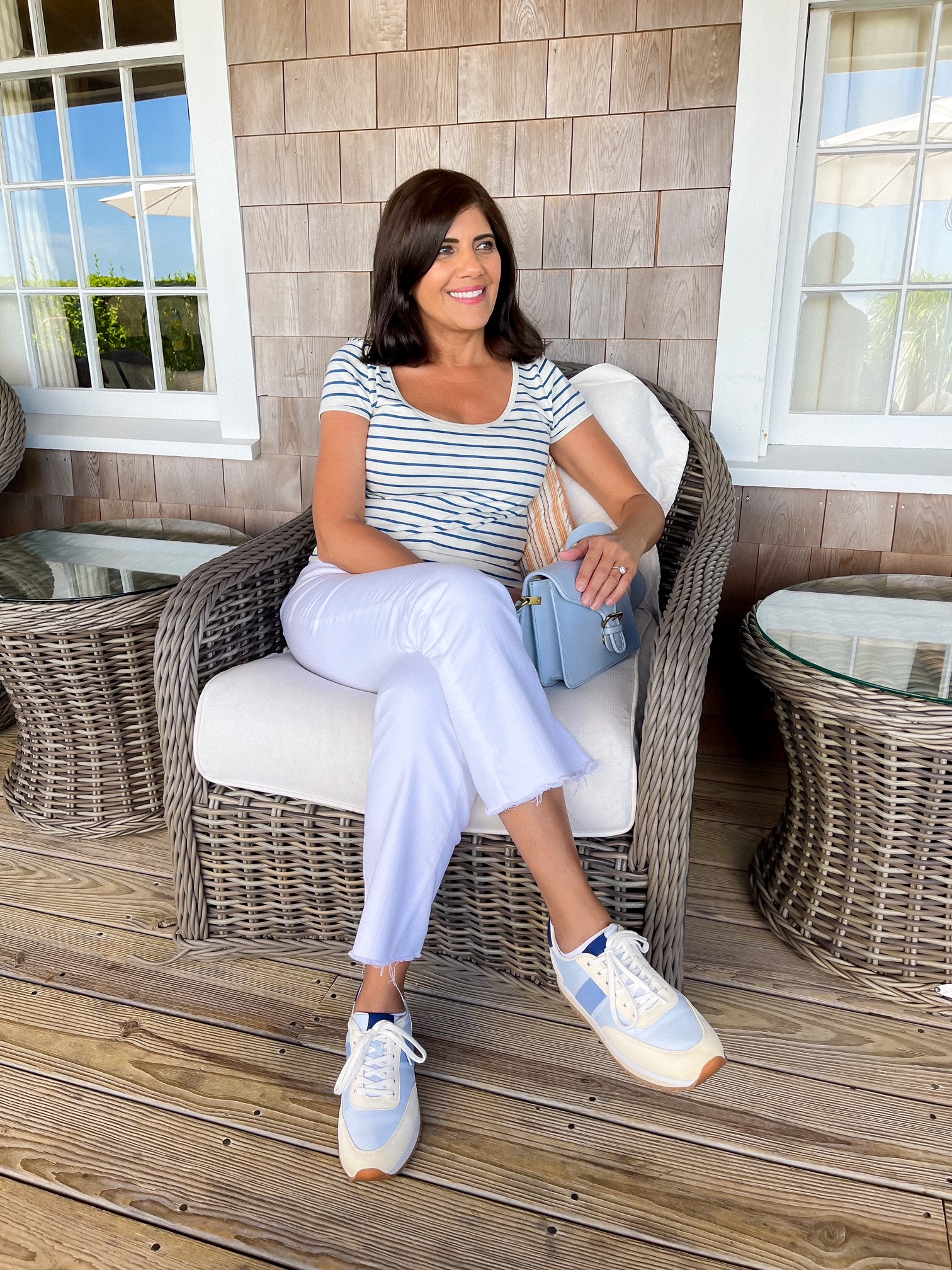 Desiree Leone wearing a coastal grandmother Nantucket travel outfit in blue and white striped shirt and white jeans.